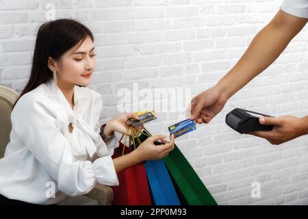 Salesman holding a credit card swipe machine or electronic data capture along with accepting credit cards from customers. Customer using credit card f Stock Photo
