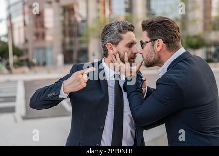 aggressive businessmen have business conflict. two businessmen have business conflict outdoor. Stock Photo