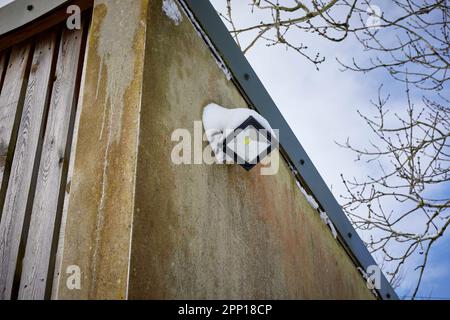 Snow covers an LED outside light in the morning after heavy overnight snow on moorland smallholding at 900ft in North Yorkshire Stock Photo