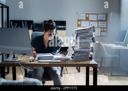 Young Businesswoman Working At Office With Stack Of Folders On Desk Stock Photo