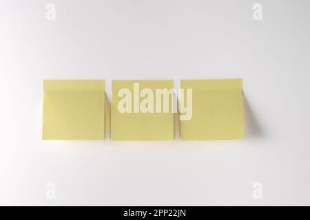 Yellow note paper on white background. Copy space. Close up. Stock Photo
