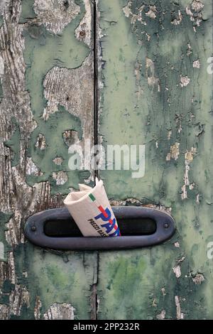 Lido di Venezia, Italy - August 19 2022: Mailbox Slit with Italian Newspaper in a Vintage Old Door with Peeled Off, Chipped Paint Stock Photo