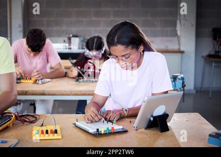 Young Latin girl student at technical high school in classroom hardware parts on circuit boards.  Stock Photo