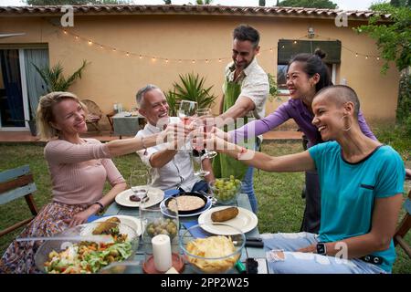 Group of friends having a barbecue in the backyard. Happy people having fun at a picnic garden.  Stock Photo