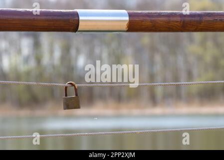 Rusty padlock hanging on a handrails steel rope Stock Photo