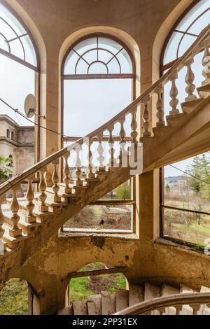 Old abandoned mansion with decorated spiral staircase. Stock Photo