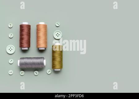 Composition with thread spools and buttons on grey background Stock Photo