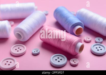 Different thread spools and buttons on pink background, closeup Stock Photo