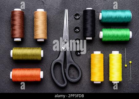 Composition with different thread spools and sewing supplies on dark background Stock Photo