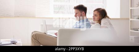 Family Couple Using Laptop On Couch Online Stock Photo
