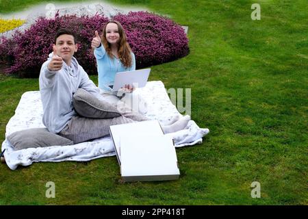 Summer holidays spend with friends there is a place for advertising text two teen teenagers showing class pizza box home delivery picnic birthday date pizza delivery ad order online fast food Stock Photo
