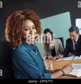 Are you doing what you love. Portrait of a businesswoman sitting in a meeting with her colleagues blurred in the background. Stock Photo
