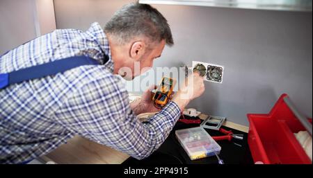 Close-up Of Person Hand Metering Socket Voltage With Digital Multimeter Stock Photo