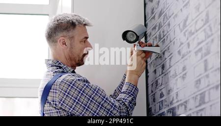 Close-up Of Technician Adjusting CCTV Camera On Wall Stock Photo