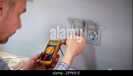 Male Electrician Checking Voltage Of Socket With Multimeter In House Stock Photo