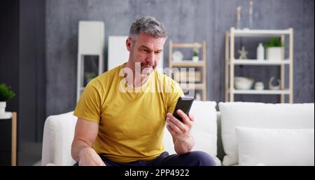 Scam Text Message. Frustrated Confused Man With Phone Stock Photo
