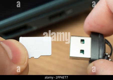 usb flash drive adapter micro sd card connection to laptop. micro sd card in a man's hand Stock Photo