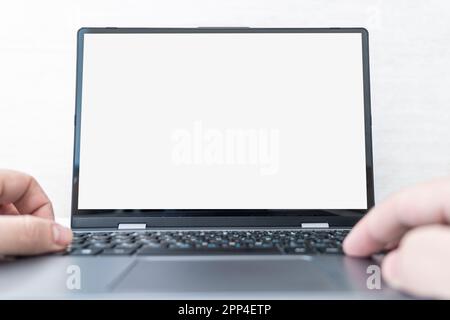 Image of Young man working in front of the laptop looking at screen with a clean white screen and blank space for text. hand typing information on key Stock Photo