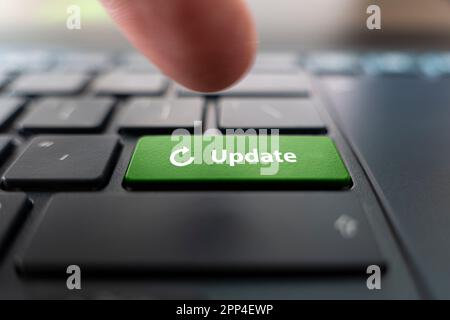 Man pressing green button with word UPDATE on modern black computer keyboard, closeup Stock Photo