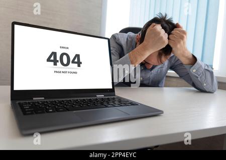 Man working on laptop, 404 error, the message on the screen page not found problem with loading the site .a sad man grabs his head with his hands. An Stock Photo