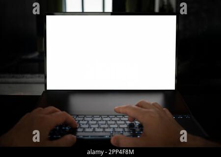 Mockup image of hands using laptop with blank white screen on table on a black background. programmer's work at night Stock Photo