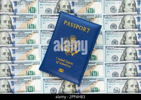 US passports in a pile of US dollar banknotes. US document. an American passport against the background of a large pile of American dollars. The conce Stock Photo