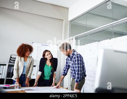 Three heads are better than two. three colleagues discussing business in the office. Stock Photo