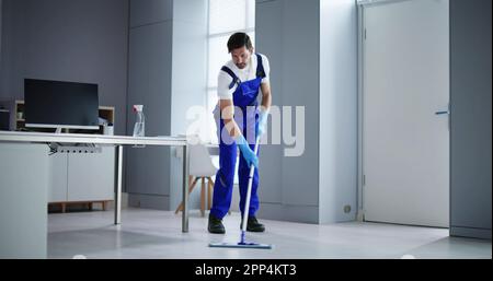 Portrait Of Happy Male Janitor Cleaning Floor At Office Stock Photo