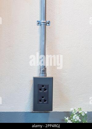 AC power socket, loft style and metal wire pipes on the concrete wall Stock Photo