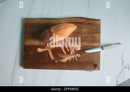 Sweet potato being prepared on wood cutting board on marble kitchen top Stock Photo