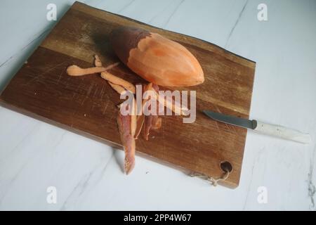 Sweet potato being prepared on wood cutting board on marble kitchen top Stock Photo