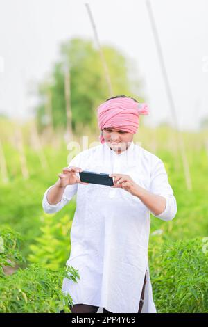 Young indian farmer showing Smart phone , Farmer talking on phone in farm, happy indian farmer Stock Photo