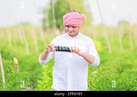 Young indian farmer showing Smart phone , Farmer talking on phone in farm, happy indian farmer Stock Photo