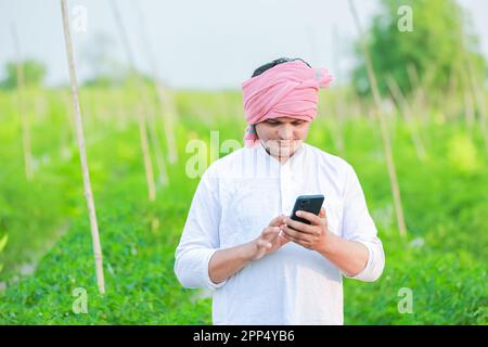 Young indian farmer showing Smart phone , Farmer talking on phone in farm, happy indian farmer Stock Photo