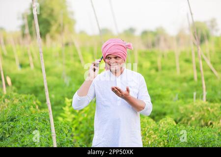 Young indian farmer showing Smart phone , Farmer talking on phone in farm, happy indian farmer Stock Photo