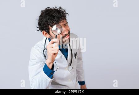 Doctor with magnifying glass looking at the camera. Doctor holding magnifying glass and looking at camera on isolated background Stock Photo