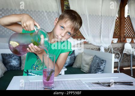 Serious kid pouring lemonade in a restaurant Stock Photo