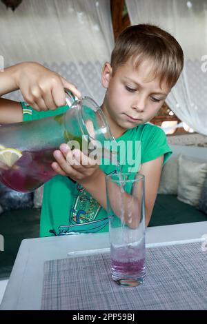 Serious boy pouring lemonade in a restaurant Stock Photo