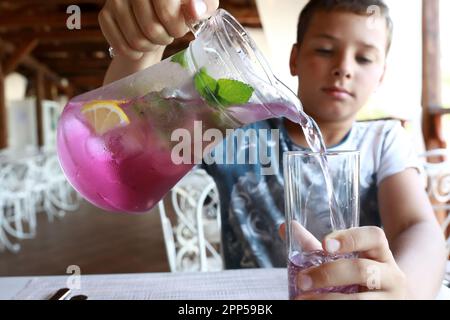 Serious child pouring lemonade in a restaurant Stock Photo