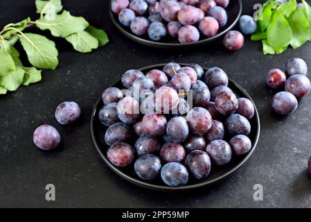 Fresh plums on plate over dark stone background Stock Photo