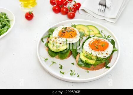 Bread with fried eggs, avocado and greens. Healthy breakfast Stock Photo