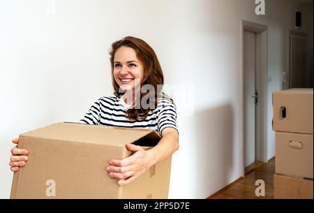 Young woman carries cardboard box , concept of moving. Stock Photo