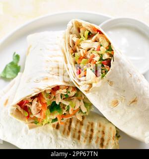 Close up view of tortilla wraps with chicken meat and fresh vegetables on plate. Stock Photo