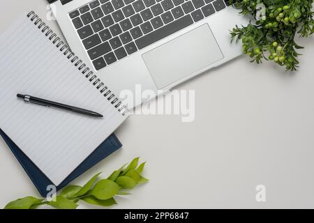 White office desk table with blank notebook, laptop and other office supplies. Top view with copy space. Stock Photo