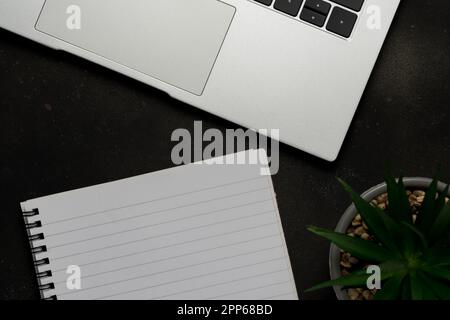 Workspace with blank notebook and laptop on black background. Top view with copy space. Stock Photo