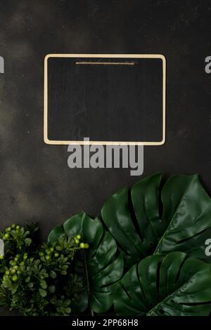 Flat lay with blank clip board with palm leaves on black background. Top view with copy space. Stock Photo