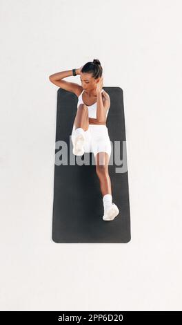 High angle of a fit woman doing abs exercises. Full length of a young female on a mat outdoors. Stock Photo