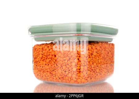 Red lentils in a plastic container, macro, isolated on a white background. Stock Photo