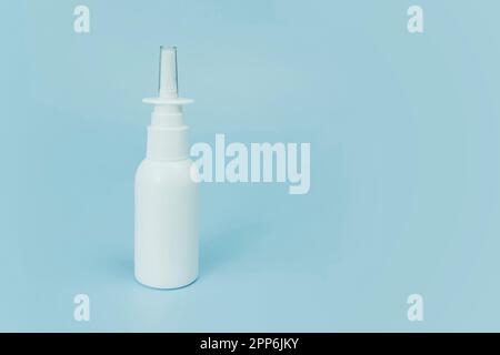 Nasal spray bottle on blue background with copy space. White plastic medical spray bottle, close-up. the concept of health medicine and pharmacy. Prod Stock Photo