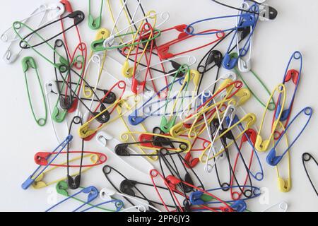 Safety pin, lots of colorful safety pin lying on a white background. Top view. Stock Photo